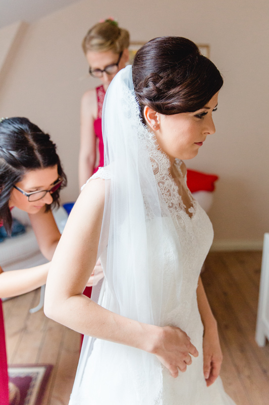 Die Trauzeugin hilft der Braut in ihr Brautkleid.
